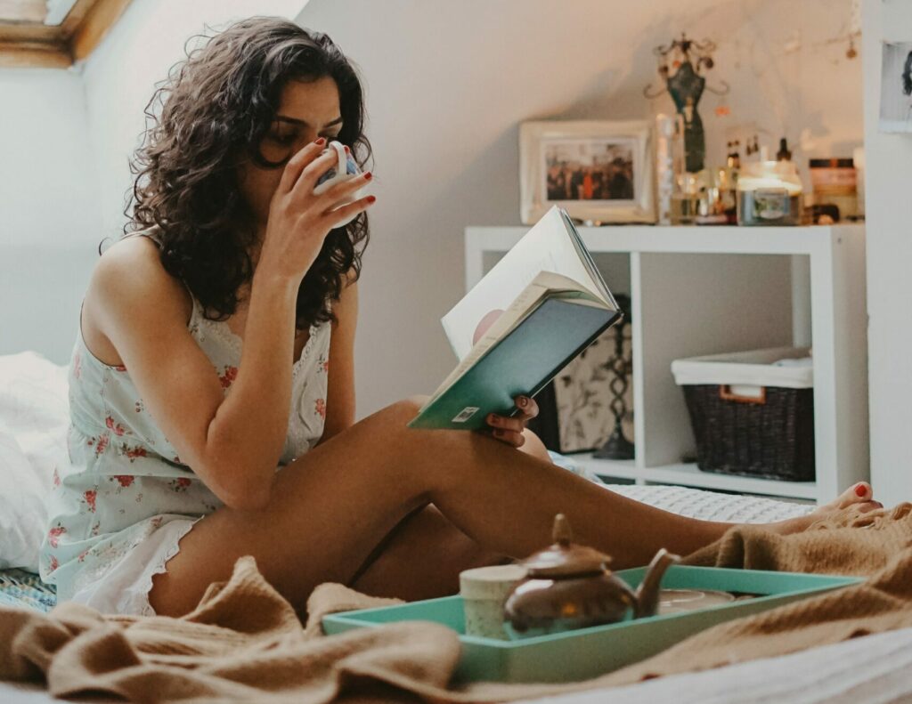 Woman drinking tea and reading in bed